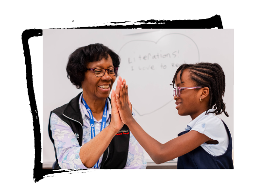 A retired adult speaking with a student high fiving